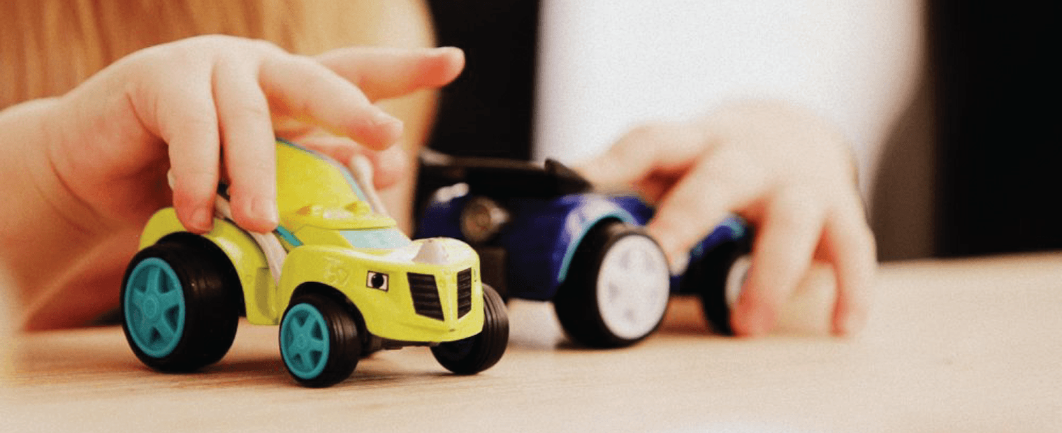 Kid playing with plastic toy cars.