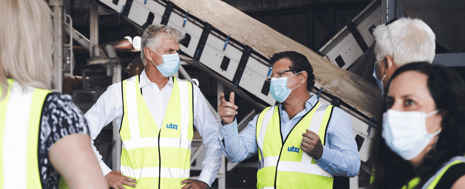 Jack (Tato) Bigion wearing protective gear discussing with colleagues at a recycling facility.