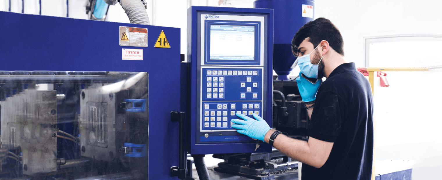 UBQ male employee wearing protective gloves and mask operating a machine.