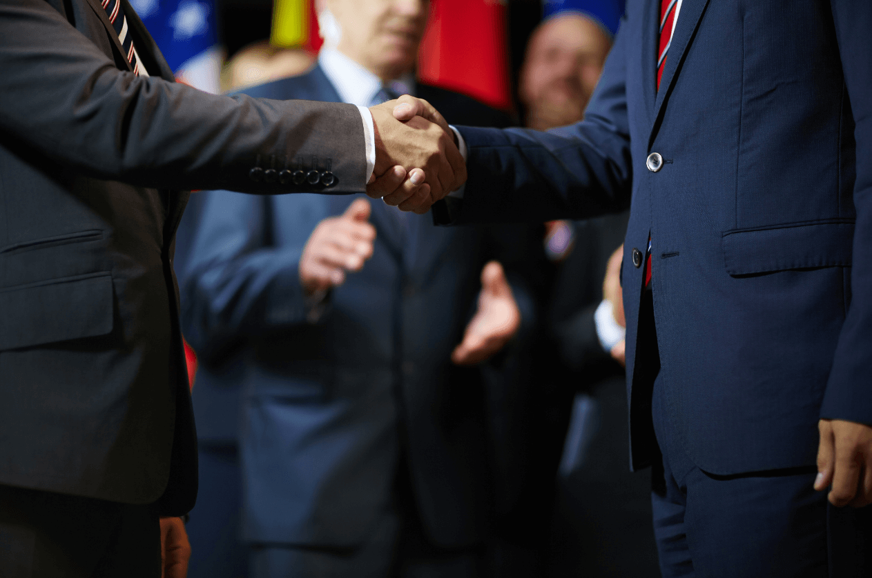 Two men wearing suits shaking hands.