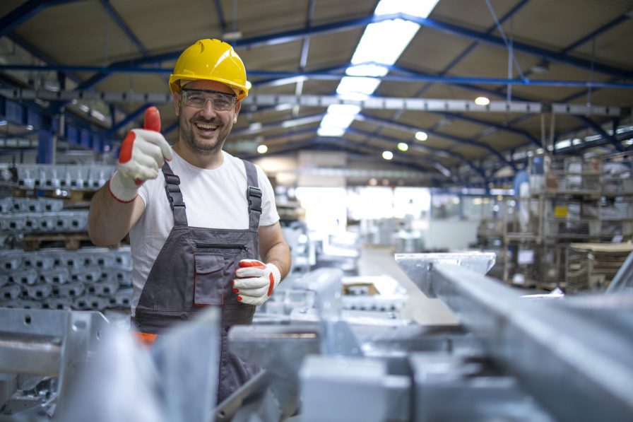 Male worker wearing protective gear at a storage facility giving thumbs up.