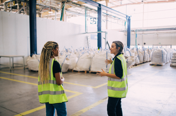 Female employees discussing circular economy at a recycling facility.