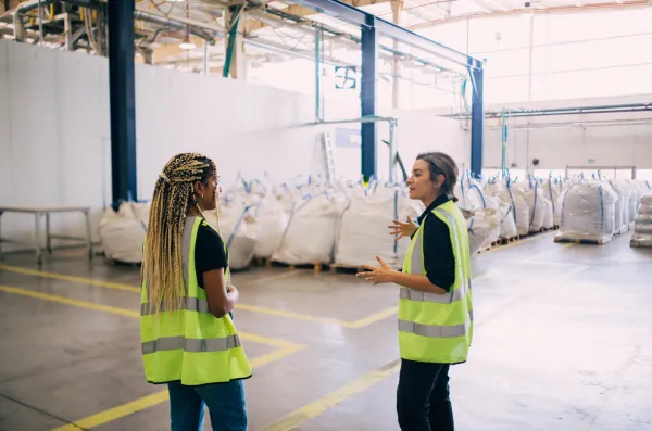 Female employees discussing circular economy at a recycling facility.