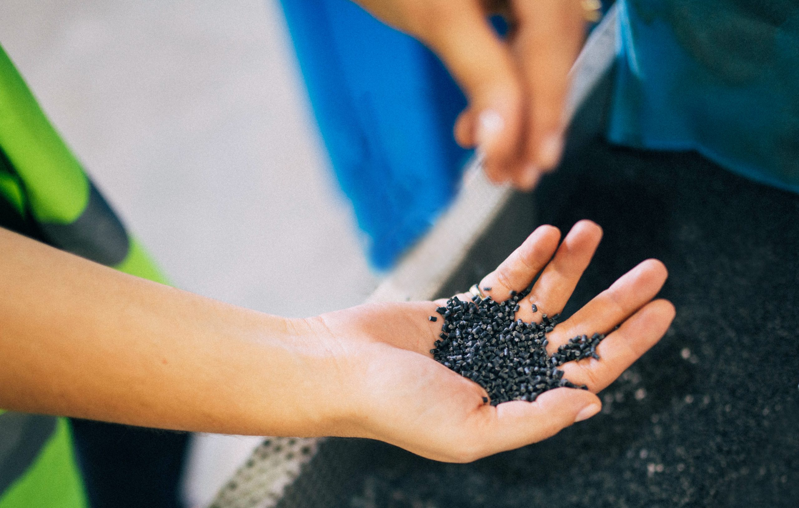 Female hand holding UBQ Material plastic pellets.