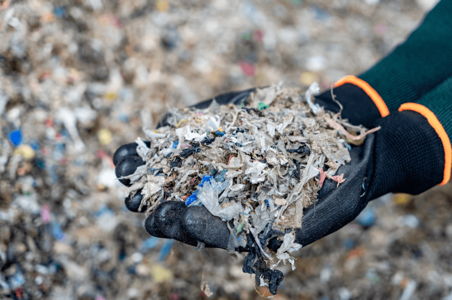 Hands wearing protective gloves holding waste.