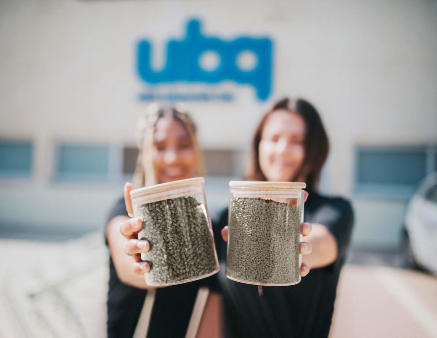 Two women extending their hands holding jars containing UBQ's additives.